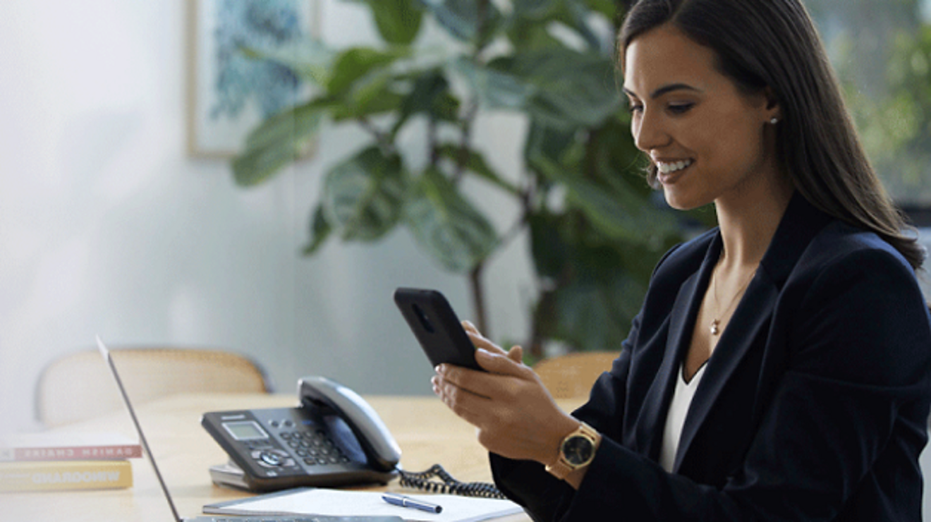 Profesional de servicios financieros sonriente usando su smartphone mientras está sentada en una sala de conferencias.