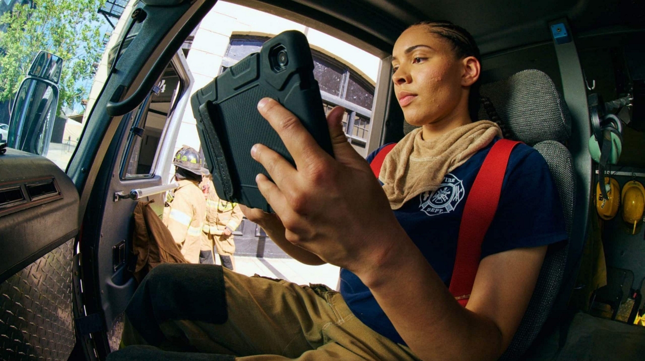 Una bombera voluntaria en su vehículo usa un dispositivo inteligente y conectividad 5G para mantenerse informada