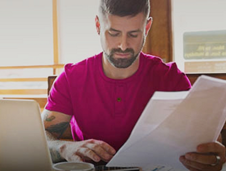 Hombre mirando papeles y una computadora