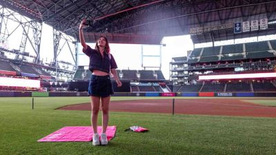 Una aficionada al béisbol toma fotos de un estadio con su teléfono móvil.