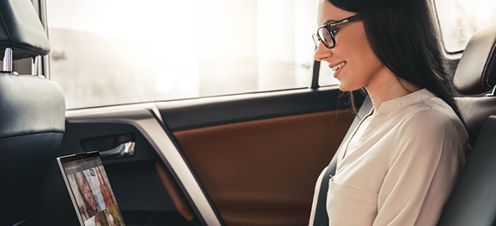 Mujer en un auto escribiendo en una laptop
