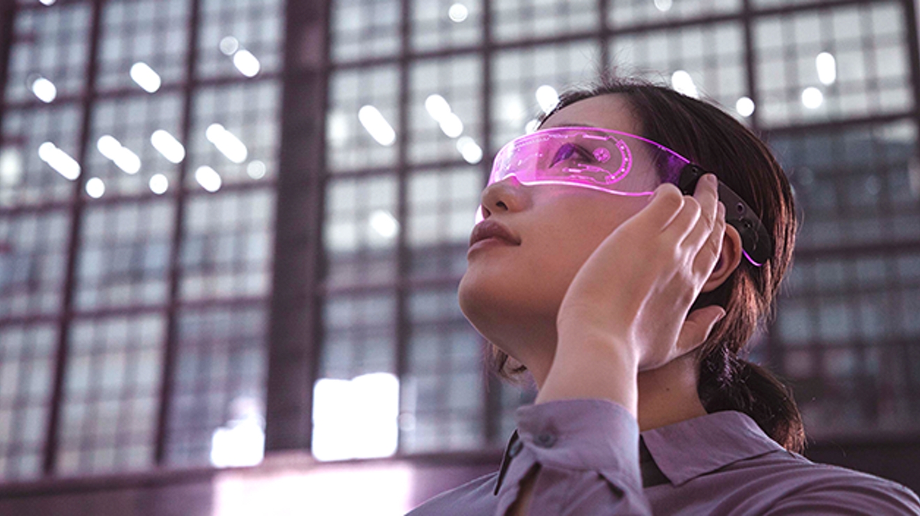Mujer joven con gafas de realidad aumentada mirando hacia arriba.