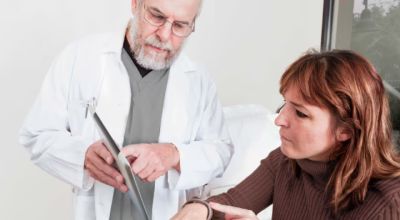 Un médico explica a su paciente el contenido de una tablet.