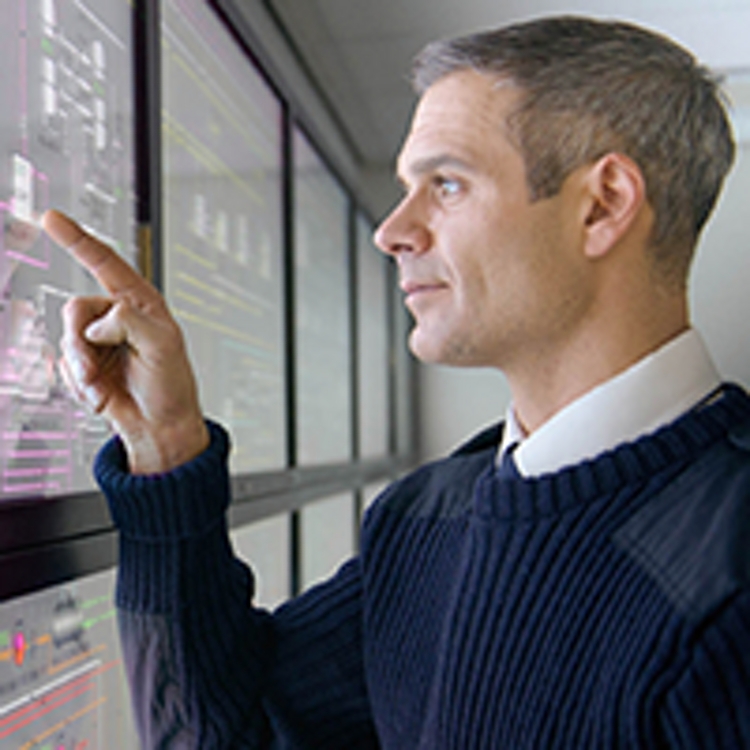 Un hombre tocando una de varias pantallas táctiles grandes con datos