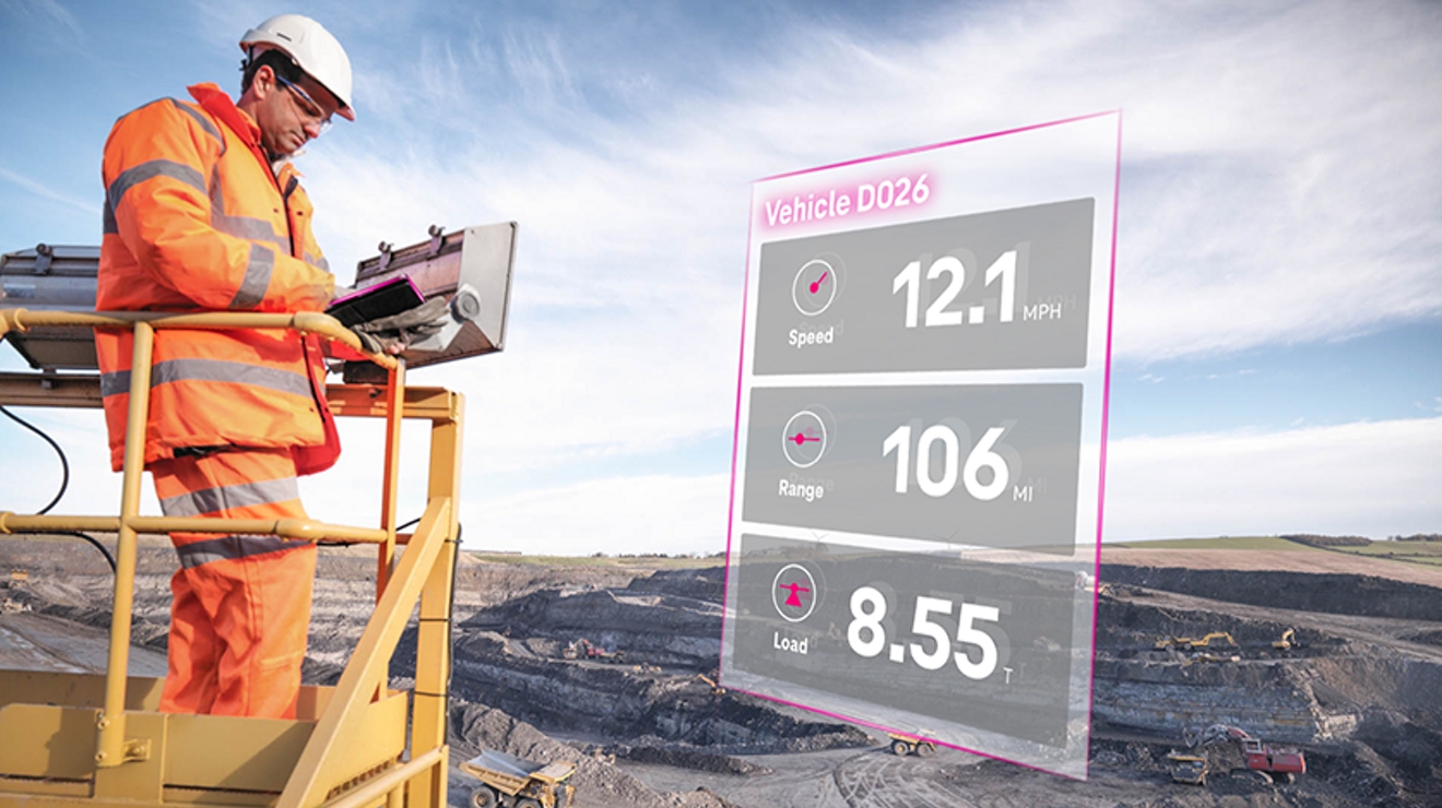 Trabajador de la construcción usa una tablet con datos en vivo para supervisar vehículos autónomos 5G en un emplazamiento minero.