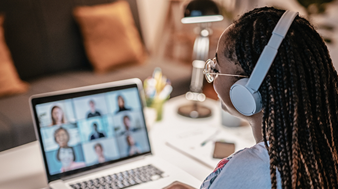 Dos estudiantes mujeres mirando a una tercera estudiantes que sostiene un visor de RV en su cabeza.