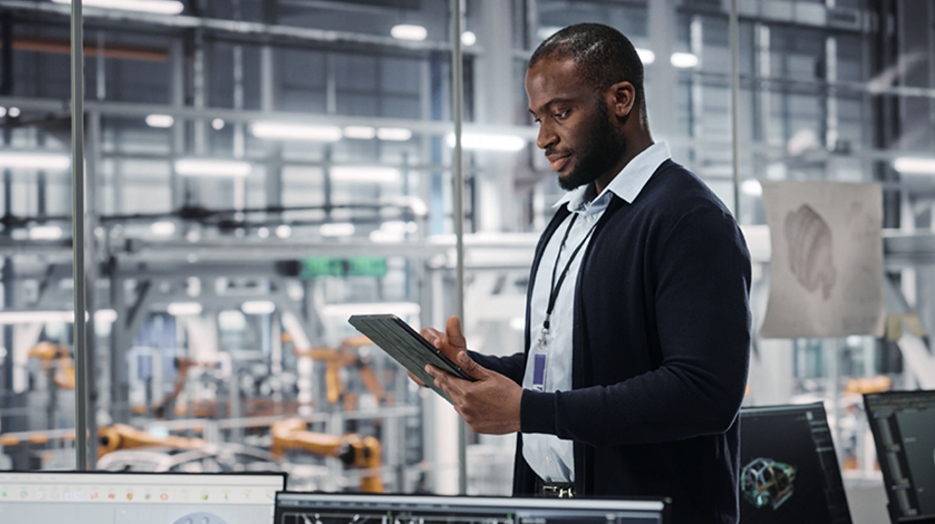 Hombre con suéter oscuro, camisa y una identificación colgada del cuello, de pie con una tablet