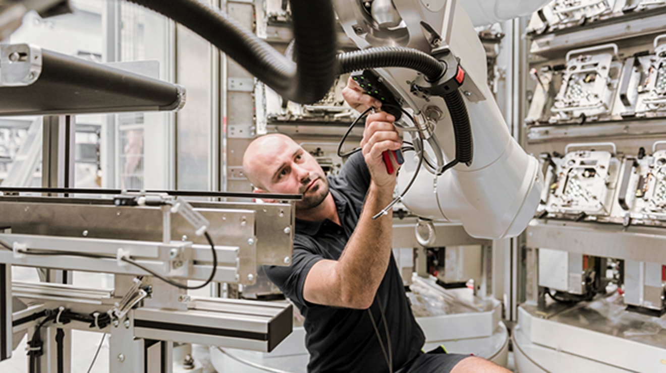 Hombre con camiseta y shorts negros trabaja en una máquina.