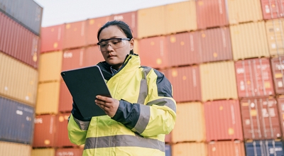 Mujer verificando contenedores importados usando una tablet.