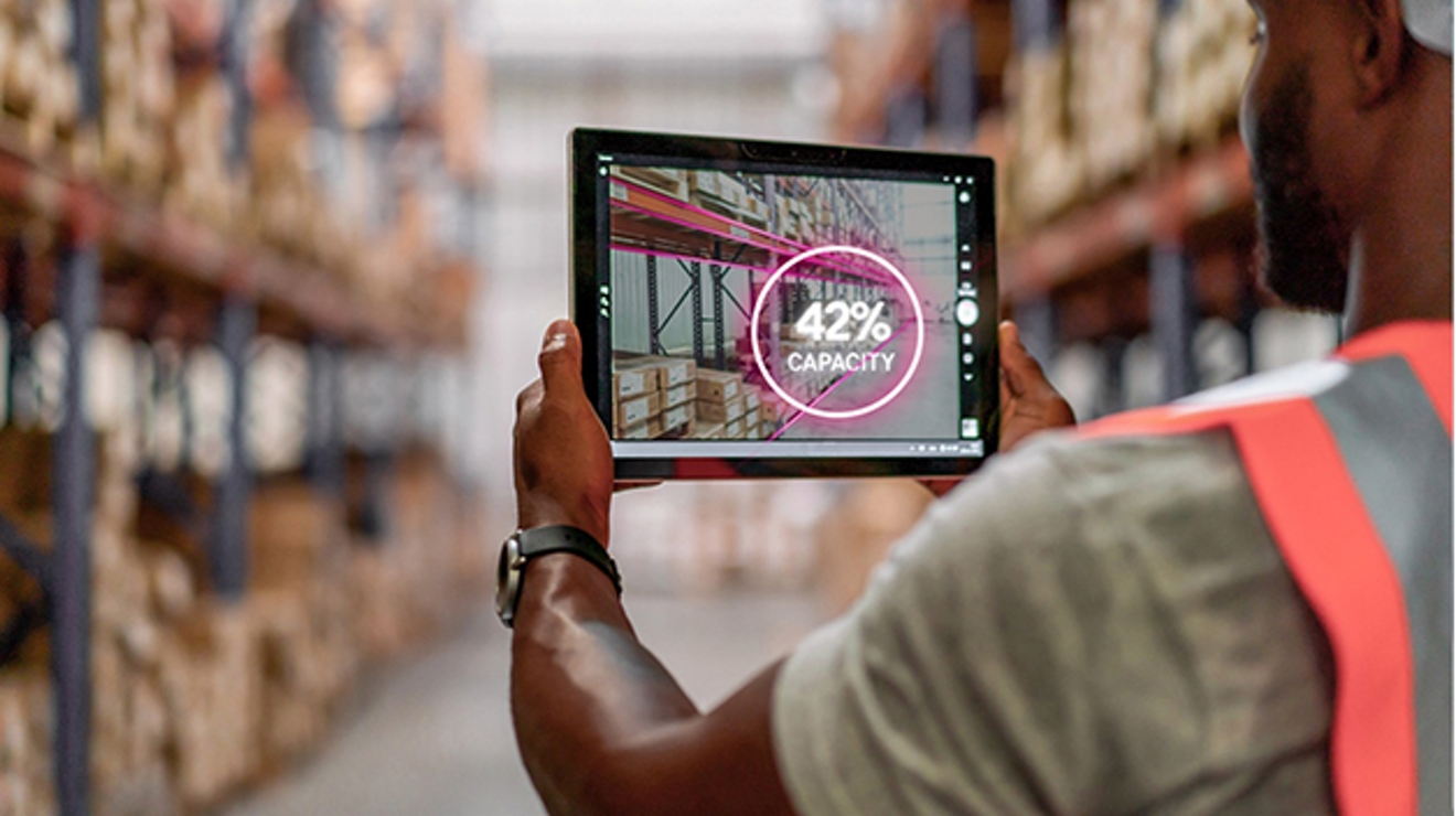 Vista por encima del hombro de un trabajador en un depósito haciendo inventario en una tablet.