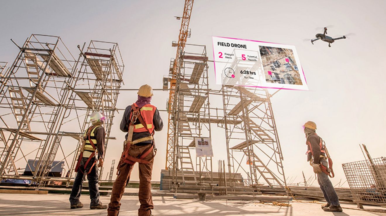 Tres trabajadores de la construcción miran hacia el cielo mientras uno controla un dron y aparecen datos virtuales en el cielo