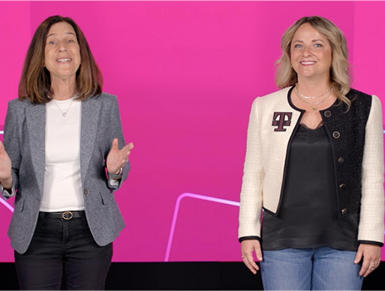 Callie Field y Susan Prescott sonríen mirando a la cámara con fondo color magenta alrededor.