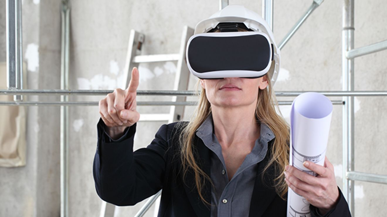 Ingeniera con planos en la mano usa un casco de RA en una obra y hace gestos en su espacio virtual.