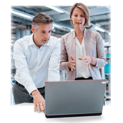 Dos compañeros de trabajo hablan sobre lo que ven en la pantalla de una laptop.