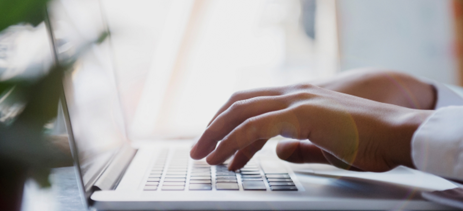 Primer plano de dos manos escribiendo en el teclado de una laptop.