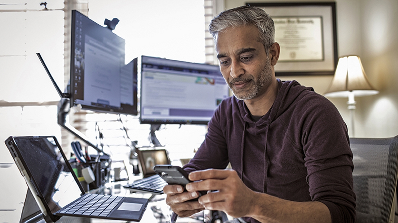 Un empleado del gobierno trabaja desde casa con una laptop conectada y su smartphone.