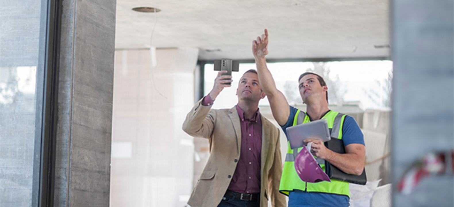 Mujer sonriente vestida de blanco toma un papel de la mano de un hombre vestido con camisa azul.