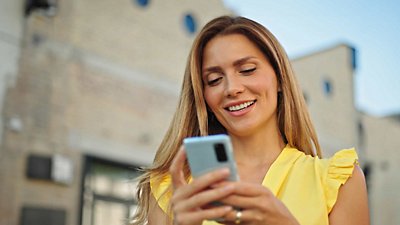 Mujer sonriente mirando su smartphone.