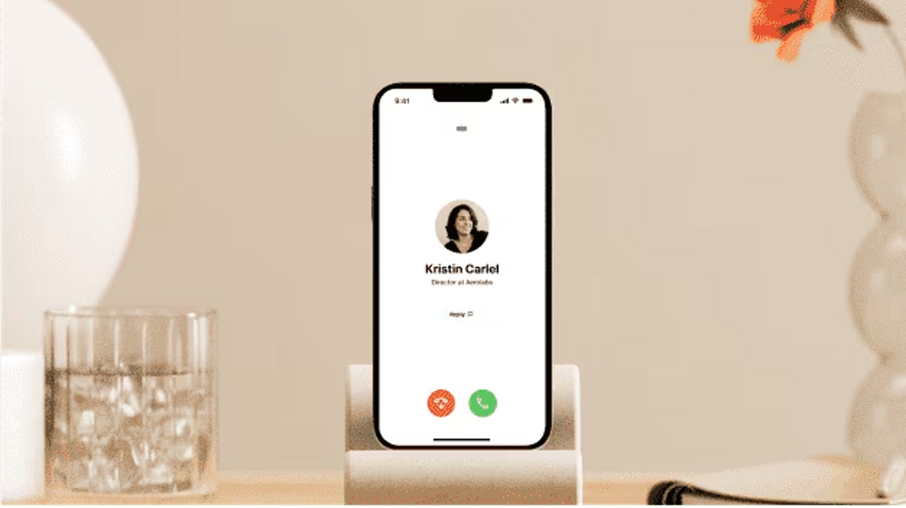 Se muestra la pantalla de llamada de voz entrante de Dialpad en un iPhone ubicado en una base para teléfono.