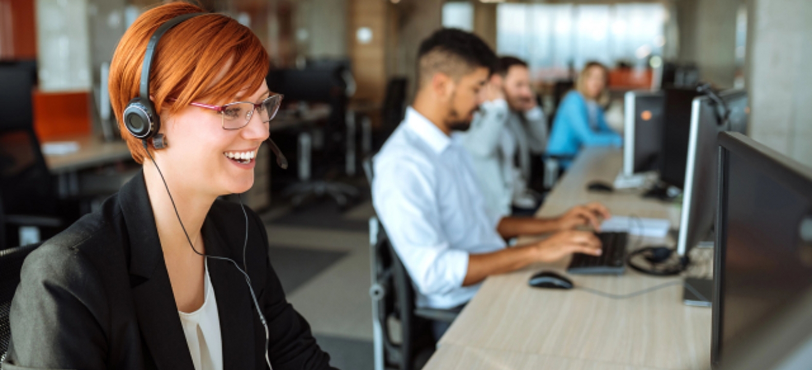 Agente de servicio al cliente durante una llamada junto a sus colegas en la oficina.