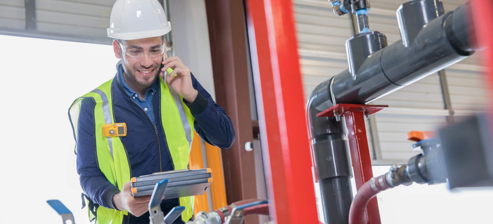 Un ingeniero de oleoductos alegre hace una llamada mientras revisa equipos.
