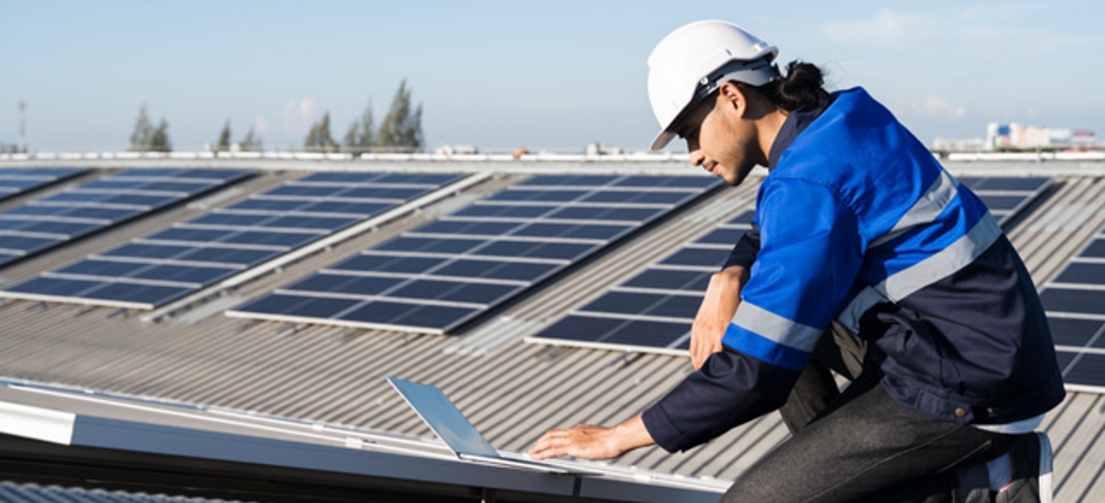 Hombre sobre un techo con paneles solares usando una chaqueta azul