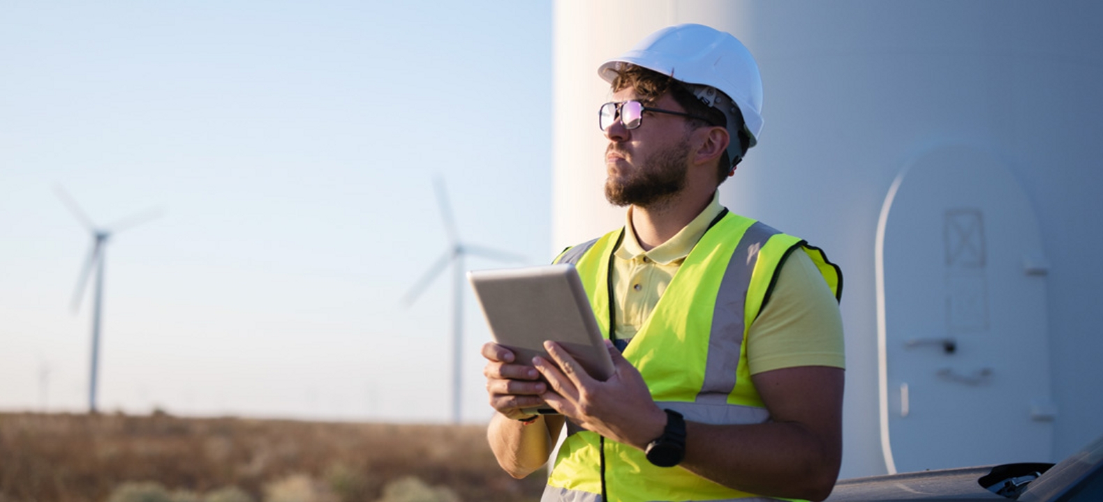 Hombre con casco blanco en un campo de aerogeneradores
