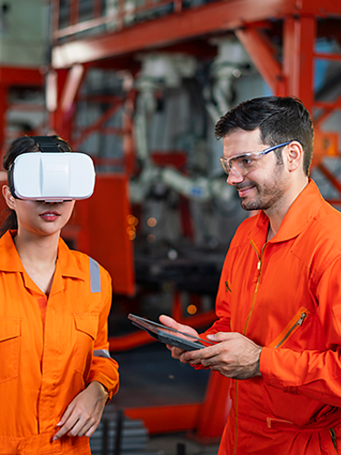 Una trabajadora con un visor de RV completando una capacitación de seguridad en el lugar de trabajo. El instructor controla su experiencia con una tablet.