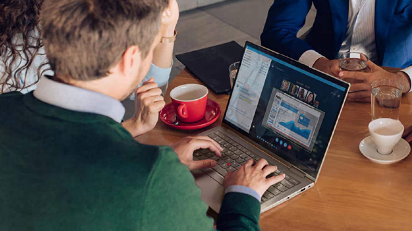 Tres colegas sentados en una cafetería asisten a una reunión en una laptop 5G segura.