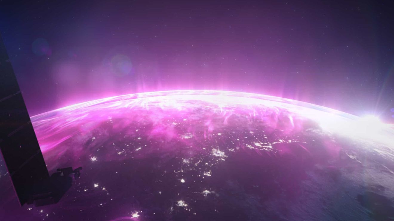 La Tierra desde el espacio, con puntos de luz visibles bajo una nube magenta de conectividad.