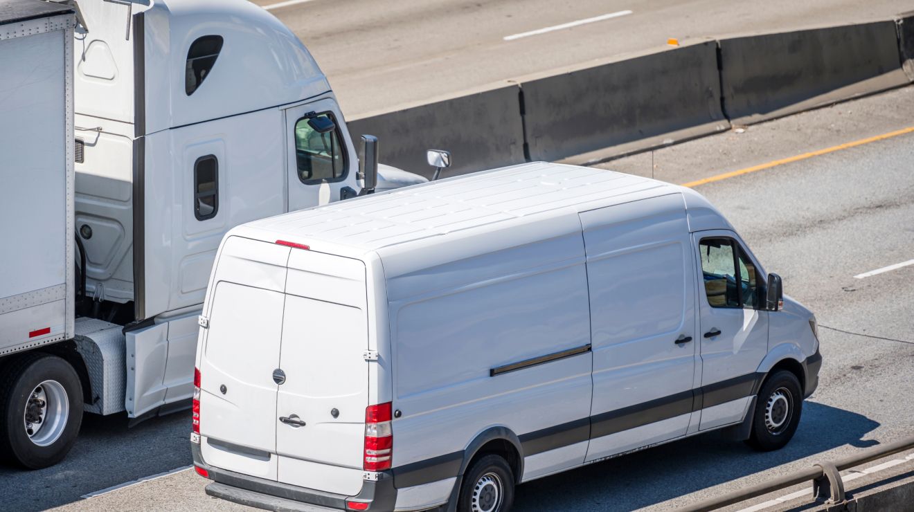 Una camioneta de entrega blanca pasa a un semirremolque blanco en una autopista.