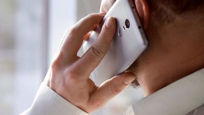 Primer plano de un profesional que sostiene un smartphone junto a su oído.