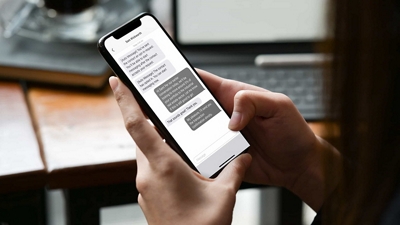 Dos manos sostienen un smartphone que muestra una conversación de texto.