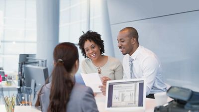 Tres profesionales colaboran con laptops y computadoras de escritorio en un elegante espacio de trabajo abierto.