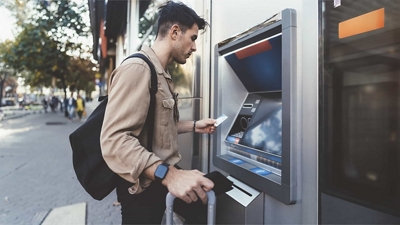 Un peatón en una calle de la ciudad realiza una transacción en un cajero automático.