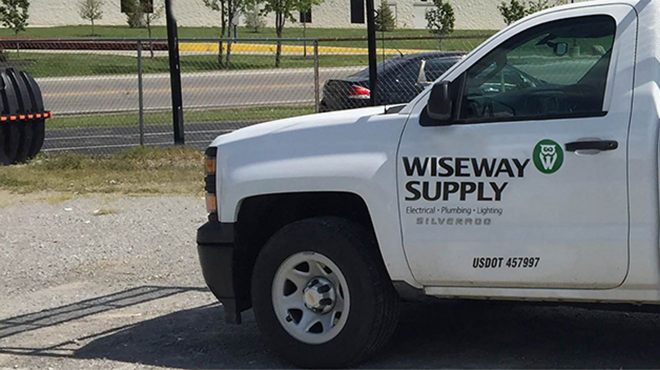 Una camioneta blanca de la empresa Wiseway Supply aparcada en un estacionamiento.