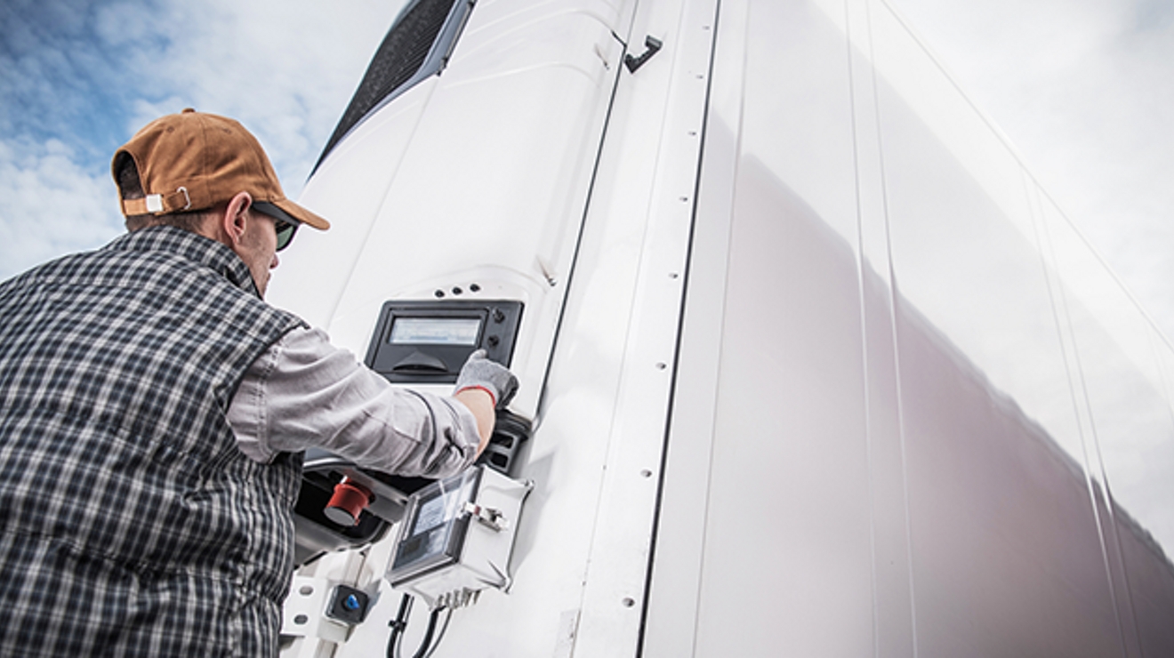 Trabajador delante de un camión usa el sistema de monitoreo de la temperatura de Spireon.
