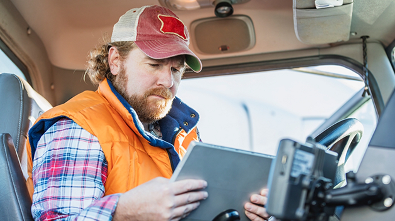 Conductor de camión en el asiento delantero mirando una tablet