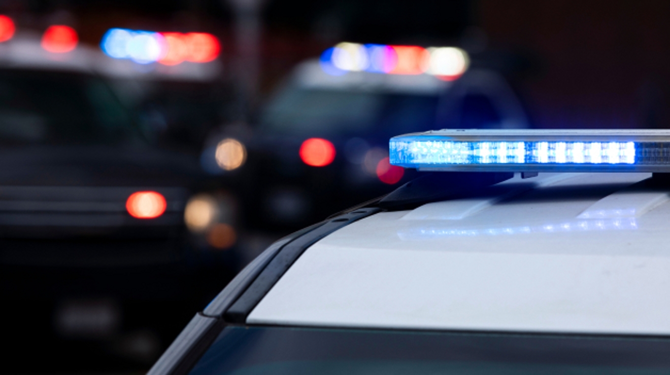 Un auto de policía con luces azules y, en el fondo, otros dos autos con luces rojas y azules.