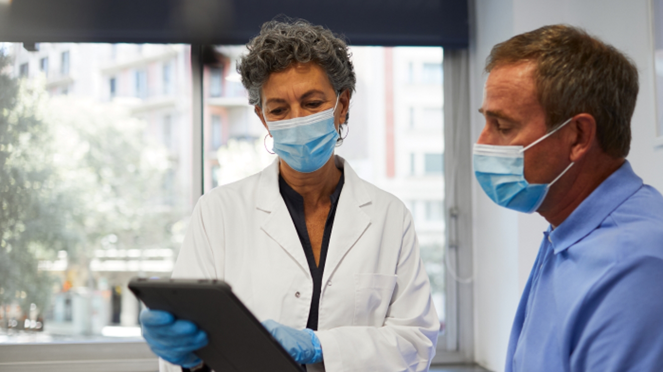 Un médico del VA conversa sobre la información de su tablet con un paciente.