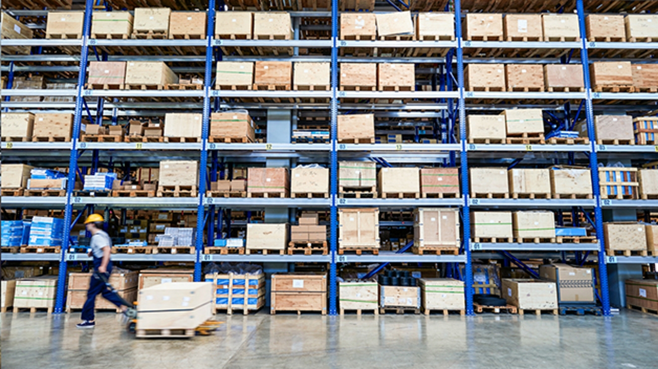 Empleado transportando un palet por un almacén.