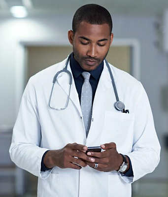 Un médico con bata y estetoscopio consulta su smartphone en un hospital.