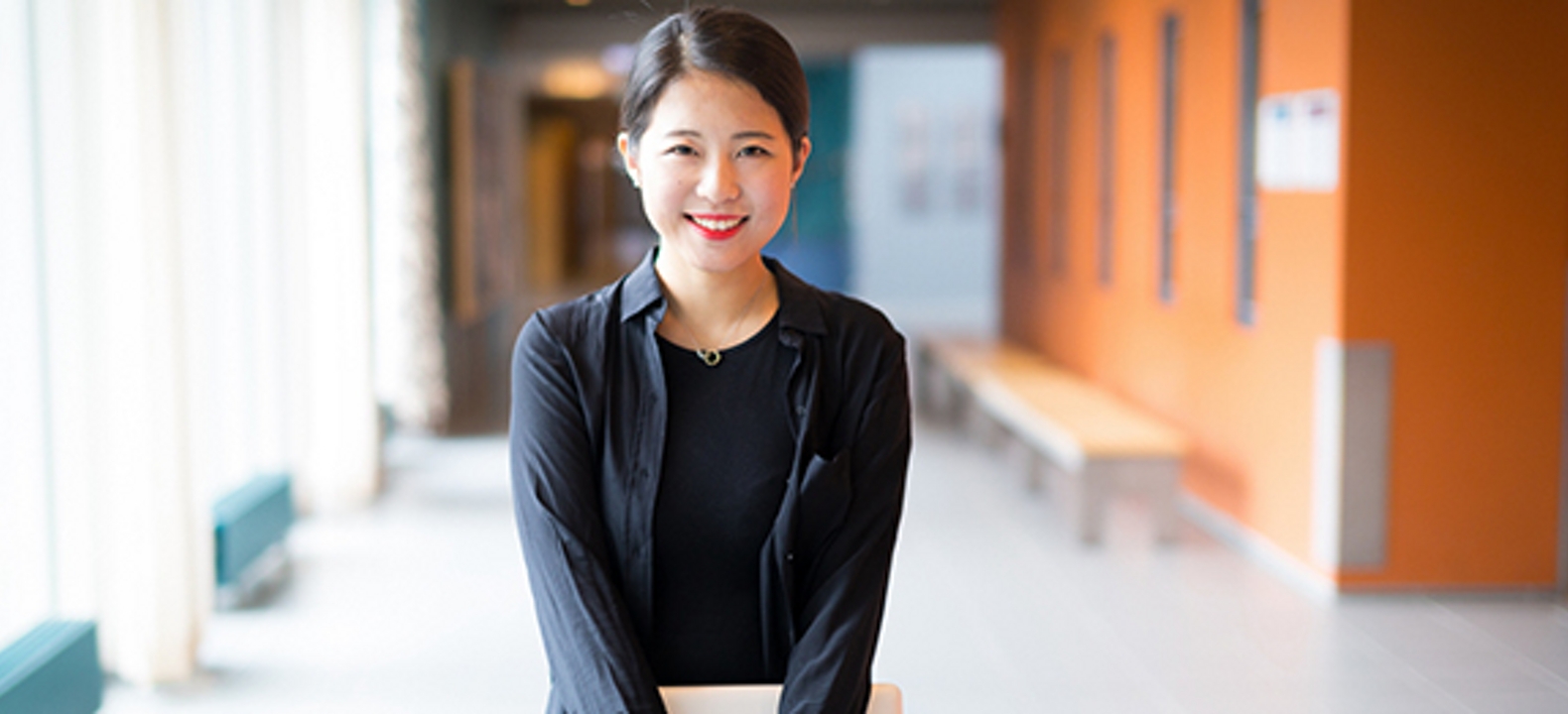 Mujer sostiene unos papeles parada en el hall de una escuela