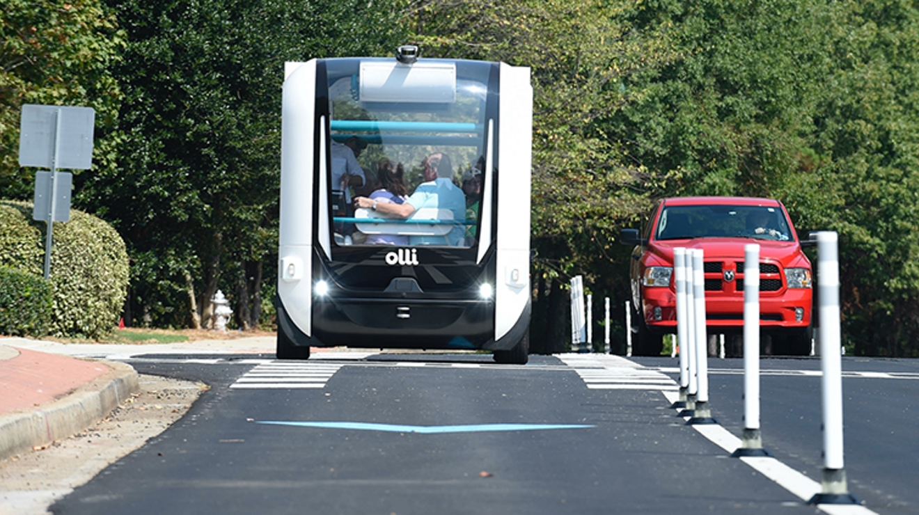 Dos personas viajan abrazadas por una calle en un vehículo de aspecto futurista.