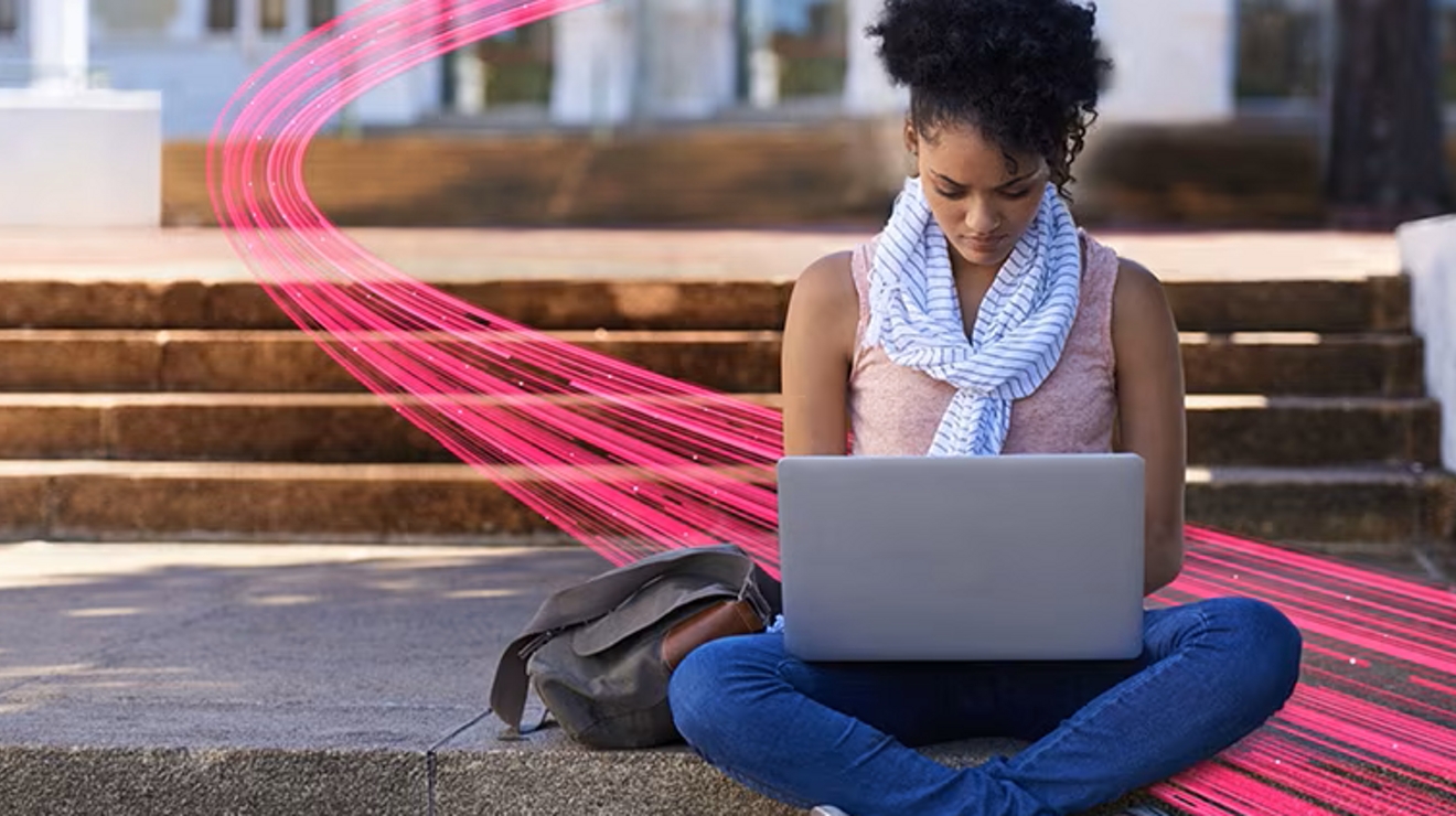 Mujer sentada con una laptop sobre la falda con un haz de luz magenta que la atraviesa