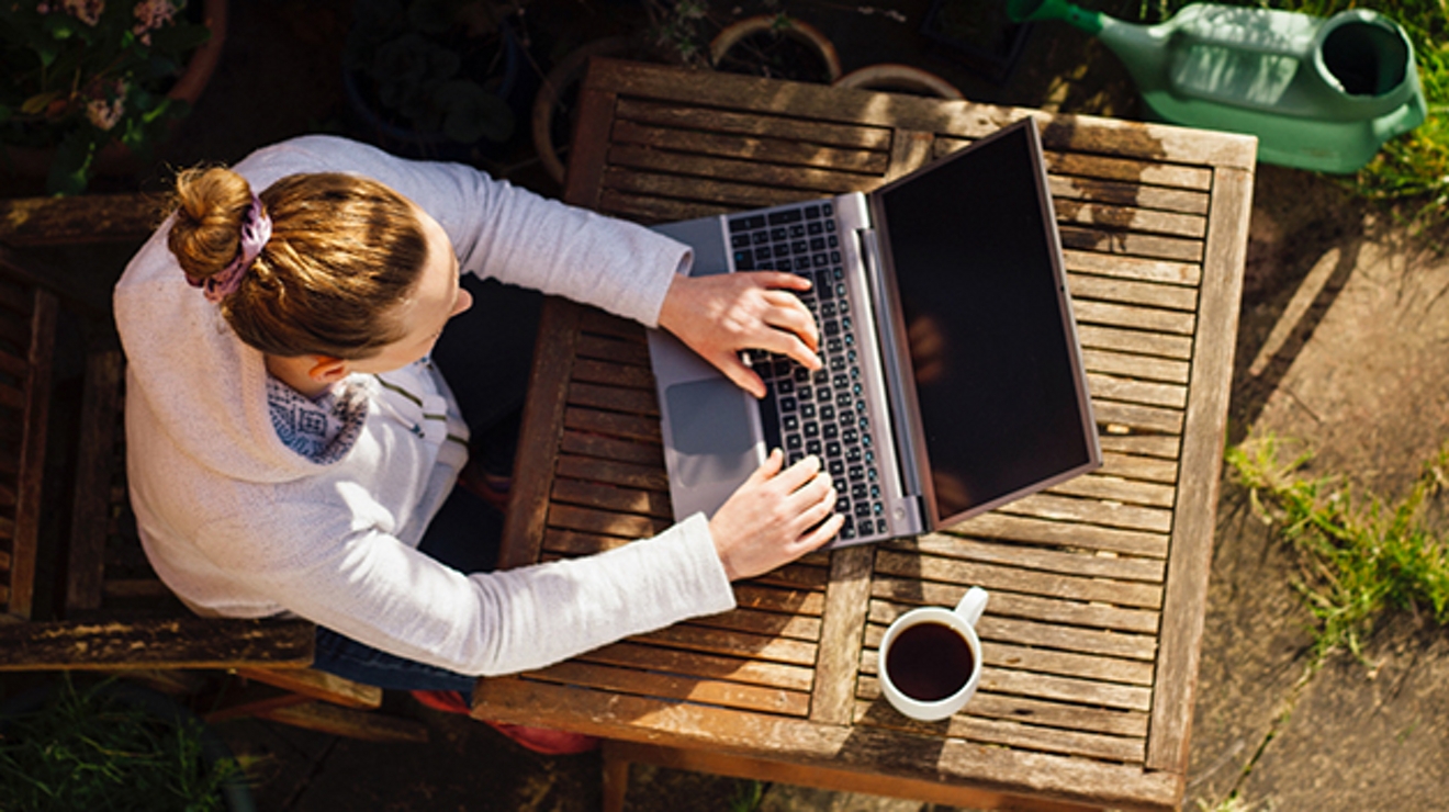 Vista aérea de una mujer trabajando al aire libre con una laptop.