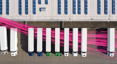 Vista aérea de una flota de camiones semirremolque con rayos magenta que indican una amplia red de conexiones.