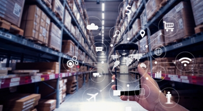 Una mano sostiene un teléfono con imágenes del pasillo de un depósito. Diferentes íconos se superponen a la pantalla y se extienden hacia afuera en forma radial.