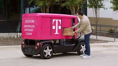 Una persona retira paquetes de un vehículo robot de mensajería CLEVON 1 totalmente eléctrico.