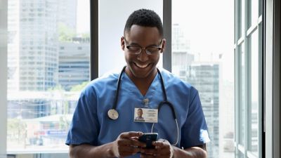 Un profesional de la salud sonriente revisa su smartphone.